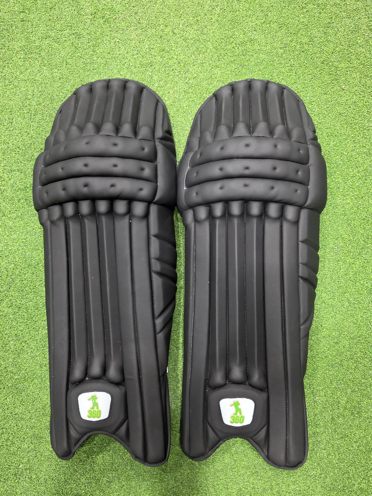 Inner back padded view of EM 360 Bull Ring adult black cricket batting pads with green trim on Alberta.