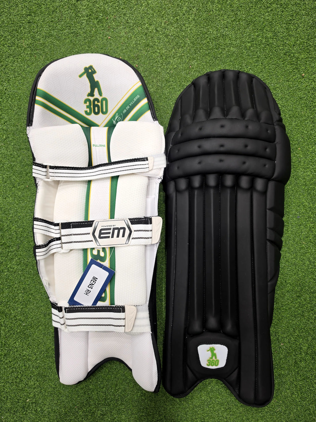 Front and inner back view of EM 360 Bull Ring adult black cricket batting pads with green accents on artificial grass on Alberta.