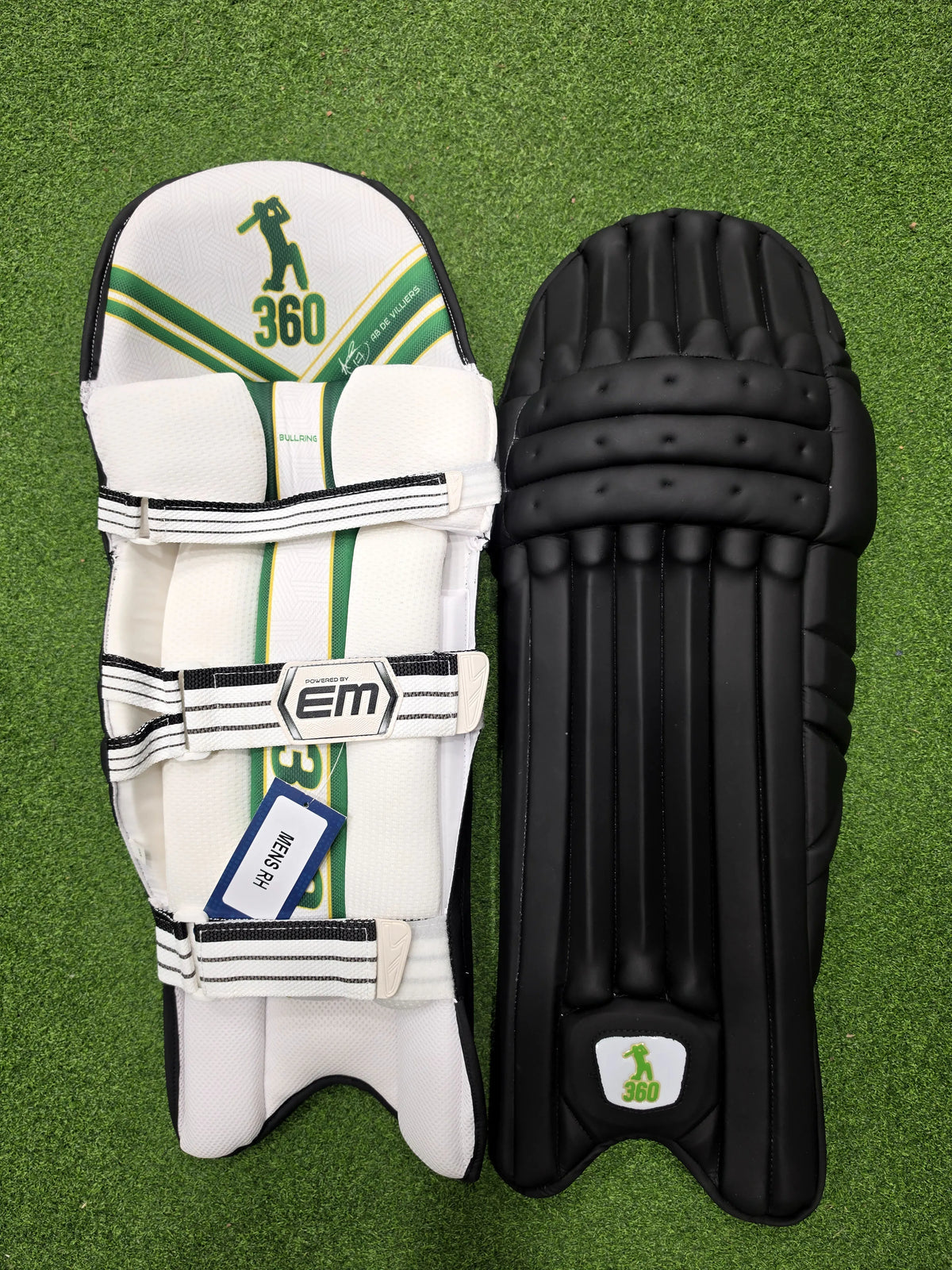 Front and inner back view of EM 360 Bull Ring adult black cricket batting pads with green accents on artificial grass on Alberta.
