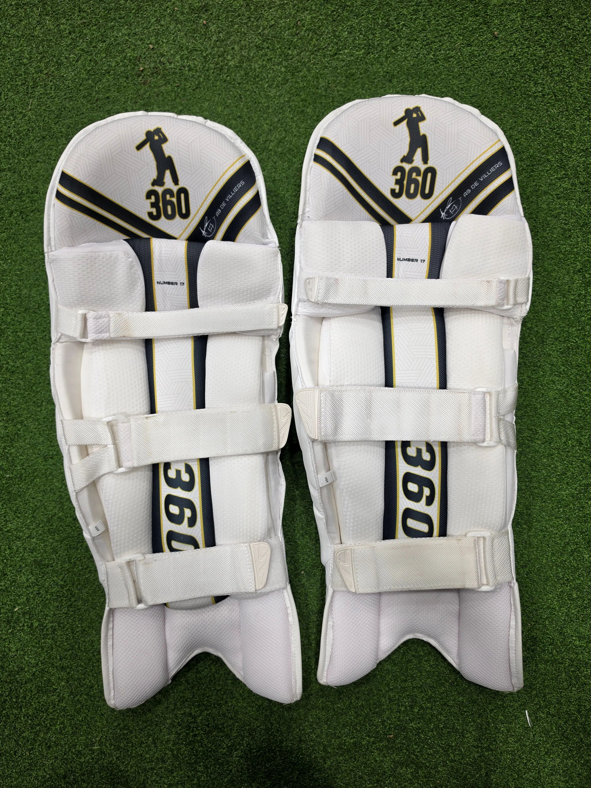 Front pair view of EM 360 No 17 adult navy blue cricket batting pads on artificial grass on Alberta.