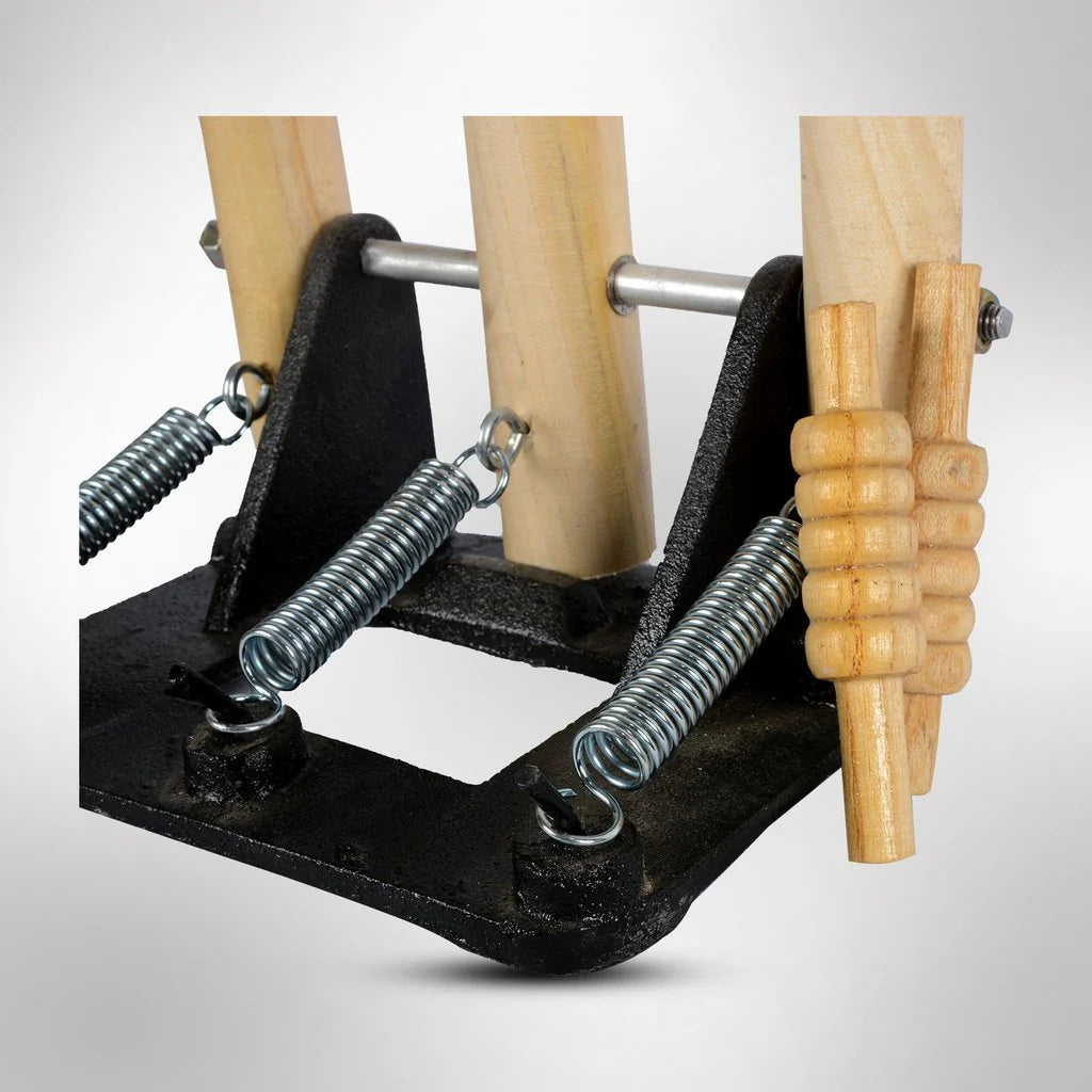 Close-up of CA Spring Return Wooden Cricket Stumps featuring a heavy-duty black cast iron base with dual tension springs and wooden bails.