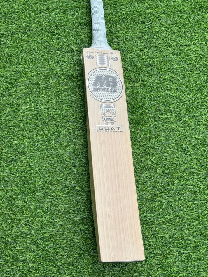 Back view of MB Malik UMZ GOAT Cricket Bat with silver stickers on green turf - Albert Cricket Store