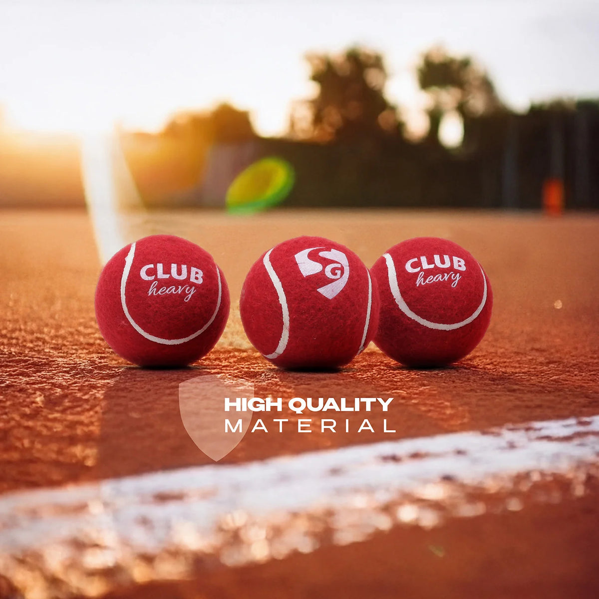 Three red SG Club Heavy tennis cricket balls placed on a cricket ground pitch showcasing high quality material.